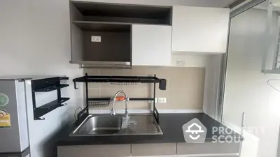 Modern kitchen with sleek cabinetry and stainless steel sink in a contemporary apartment.