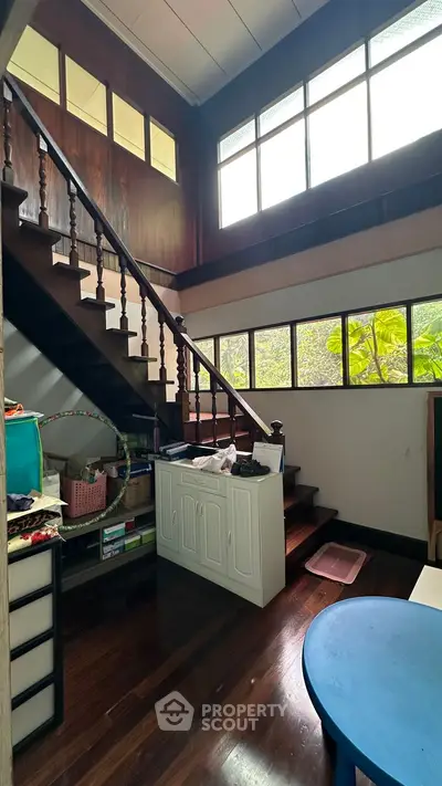 Charming interior with wooden staircase and large windows, perfect for natural light lovers.