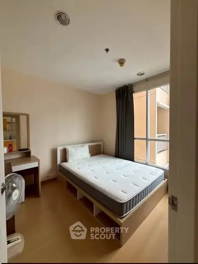 Cozy bedroom with natural light, featuring a comfortable bed and modern furnishings, ideal for restful living.