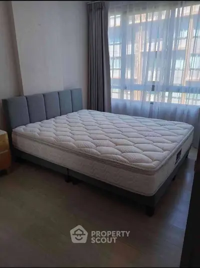 Spacious bedroom with large window and comfortable bed, perfect for relaxation.