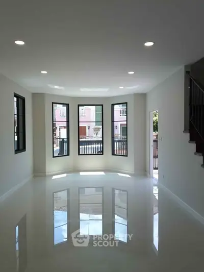 Spacious living room with large windows and glossy floors in modern home