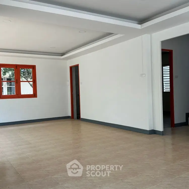 Spacious empty room with large windows and tiled flooring, ready for customization.