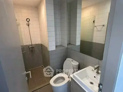 Modern bathroom with sleek design featuring shower, toilet, and sink.