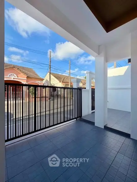 Charming residential entrance with modern gate and tiled flooring, offering a welcoming outdoor space.