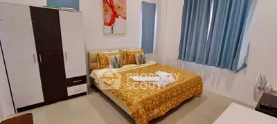 Cozy bedroom with stylish decor and ample natural light, featuring a comfortable bed and modern wardrobe.