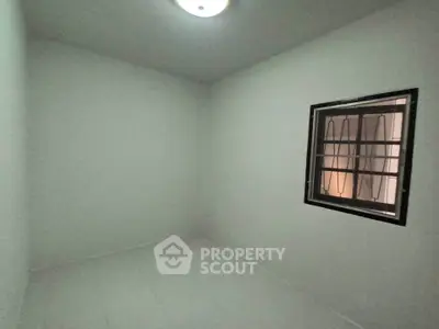 Minimalist small room with window and white walls, ideal for storage or compact living space.