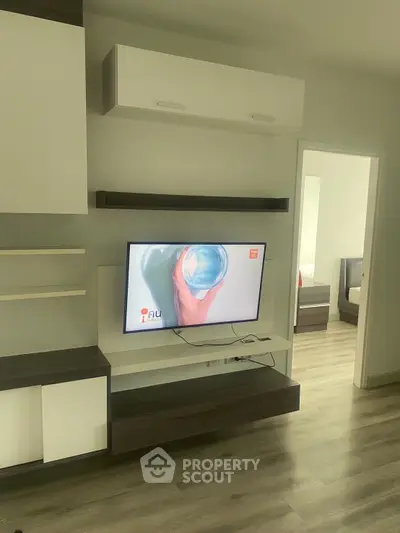 Modern living room with sleek TV unit and open doorway to bedroom, showcasing stylish flooring.