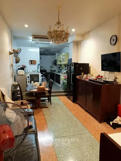 Charming living room with vintage decor and open kitchen layout, featuring a chandelier and modern appliances.