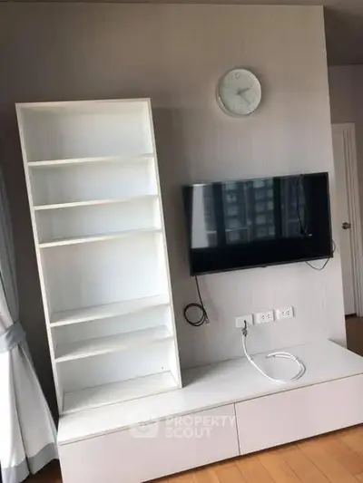 Modern living room with wall-mounted TV and sleek white shelving unit