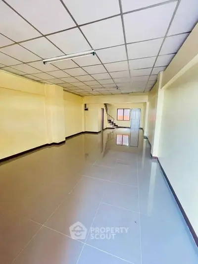 Spacious open-plan interior with tiled flooring and staircase, ideal for versatile use.
