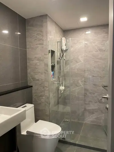 Modern bathroom with sleek gray tiles and glass shower enclosure
