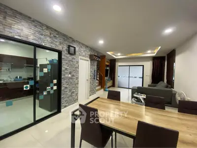 Modern open-plan living and dining area with stylish stone accent wall and sleek furniture.