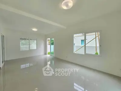 Spacious and bright living room with large windows and glossy tiled floors.