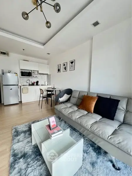Modern living room with stylish decor, open kitchen, and cozy seating area.