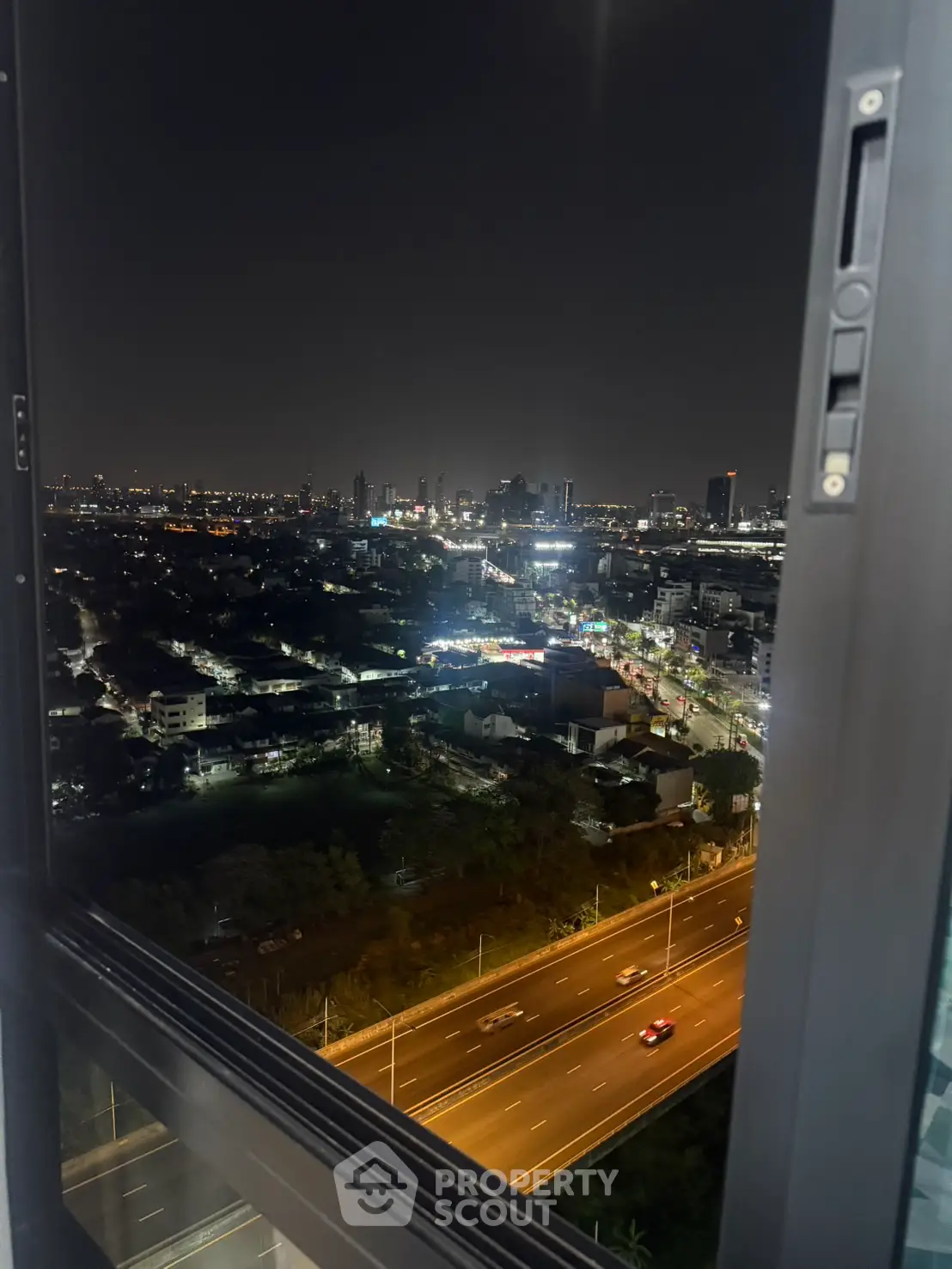 Stunning cityscape night view from high-rise window overlooking busy highway.