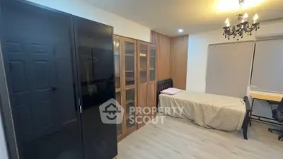 Cozy bedroom with modern wardrobe and elegant chandelier lighting.