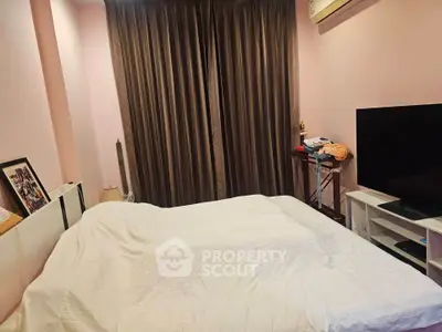 Cozy bedroom with modern decor and large TV, perfect for relaxation.