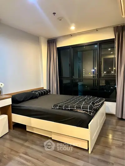 Modern bedroom with stylish decor and large window offering city views