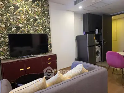Stylish living room with modern decor, featuring a TV, sofa, and open kitchen with appliances.