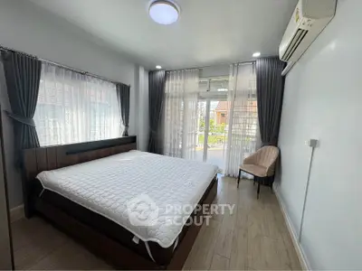 Spacious bedroom with large windows and balcony access, featuring modern decor and ample natural light.