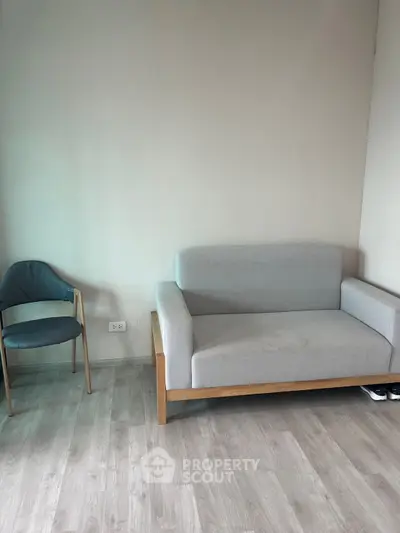 Minimalist living room with modern furniture and wooden flooring.