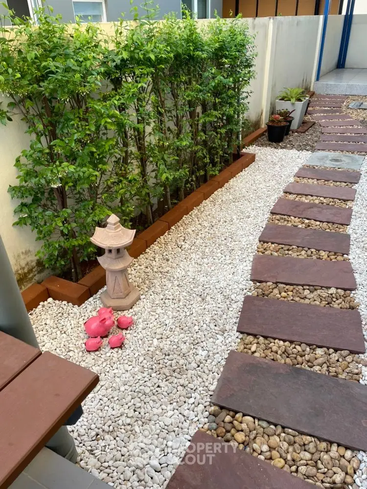Charming garden path with decorative stones and lush greenery, perfect for tranquil outdoor living.