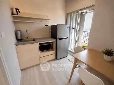 Modern compact kitchen with dining area and balcony view in urban apartment