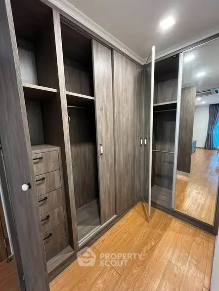 Spacious walk-in closet with wooden finish and mirrored sliding doors.