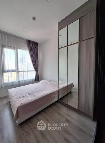Modern bedroom with large window and mirrored wardrobe in a stylish apartment.