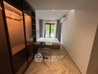 Modern bedroom with stylish furniture and balcony view, featuring elegant wood flooring.