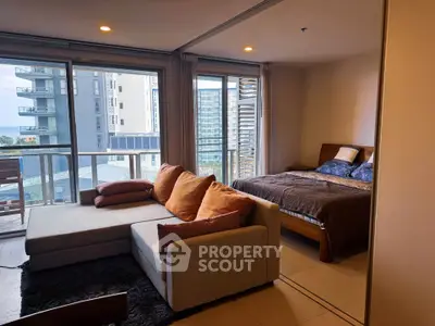Modern apartment with spacious living room and bedroom, featuring large windows and a balcony with city views.