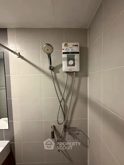 Modern bathroom with sleek showerhead and tiled walls, perfect for a contemporary home.