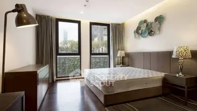 Modern bedroom with large windows and stylish decor in urban apartment.