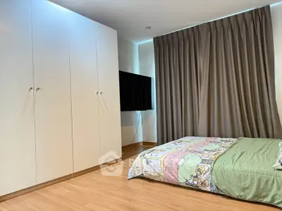 Cozy bedroom with modern wardrobe and flat-screen TV, perfect for relaxation.