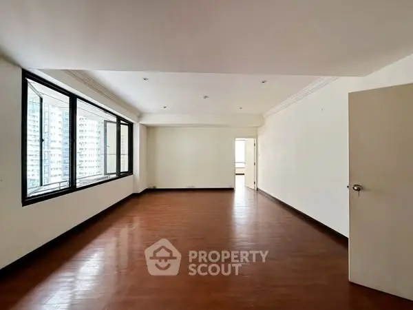 Spacious empty living room with large windows and wooden flooring