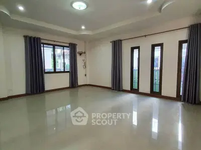 Spacious empty living room with large windows and modern ceiling lights.