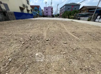 Vacant land plot in urban area ready for development with surrounding buildings.