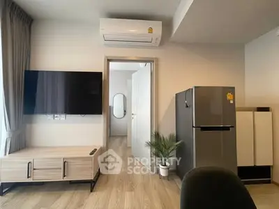 Modern living room with air conditioning, flat-screen TV, and sleek refrigerator in a stylish apartment.