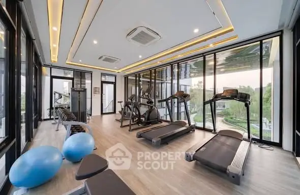 Modern gym with large windows and state-of-the-art equipment in luxury residential building.