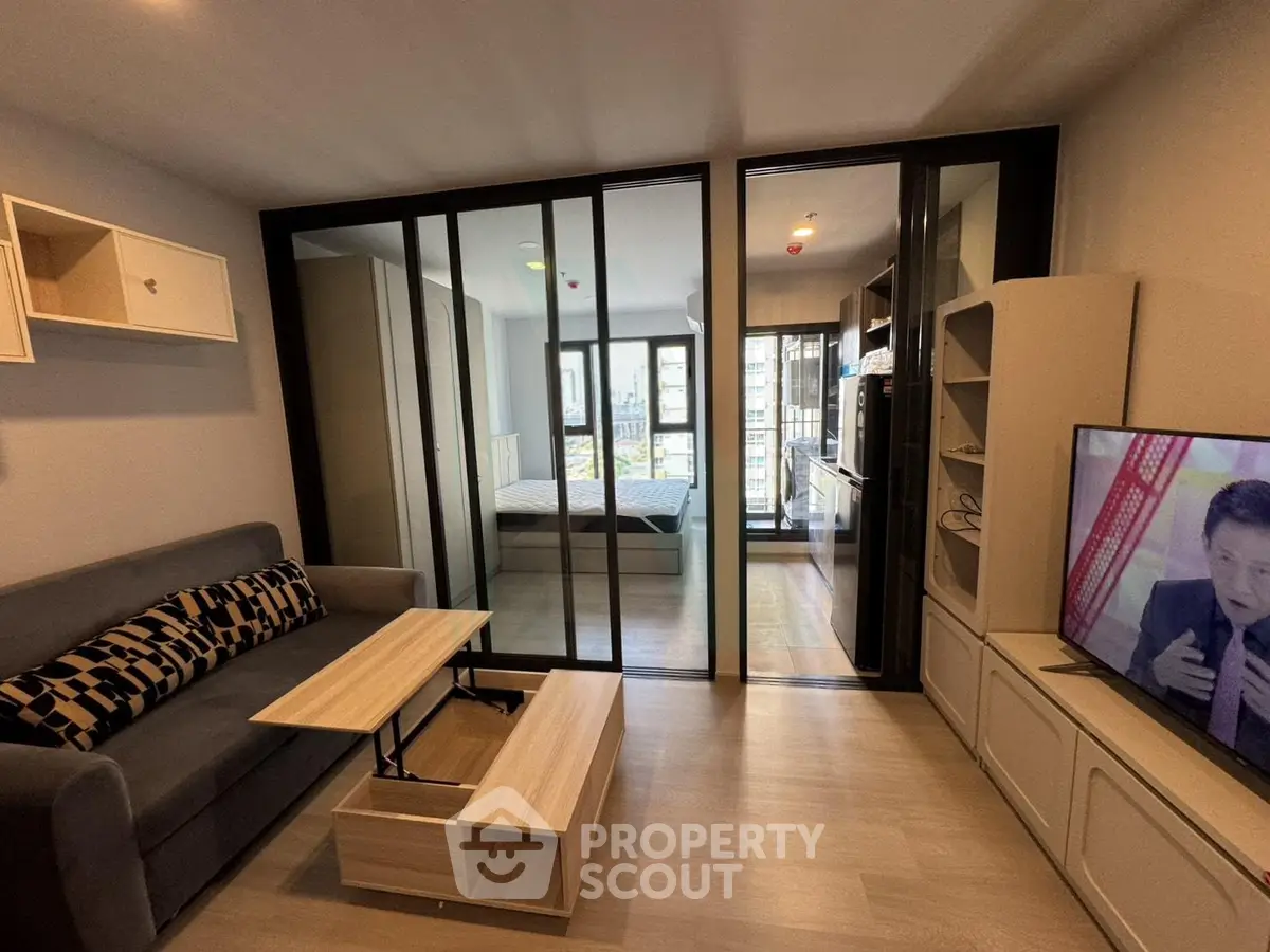 Modern living room with sliding glass doors to bedroom, stylish furniture, and TV