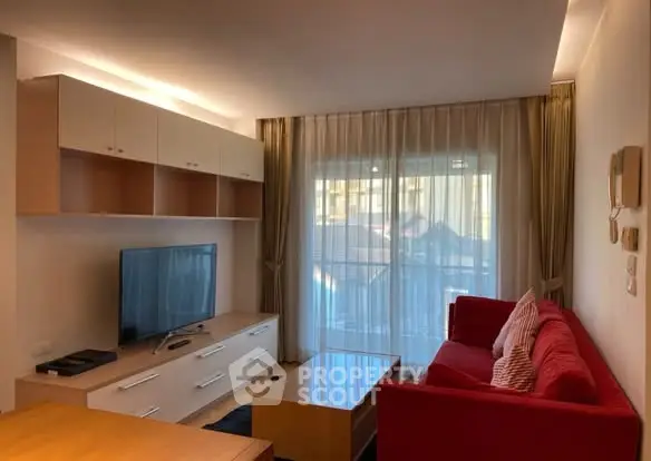 Modern living room with red sofa, TV, and stylish lighting in a cozy apartment.
