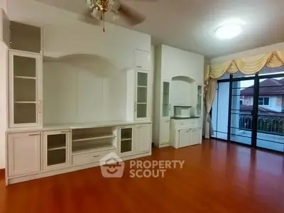 Spacious living room with built-in cabinets and large windows overlooking a residential view.