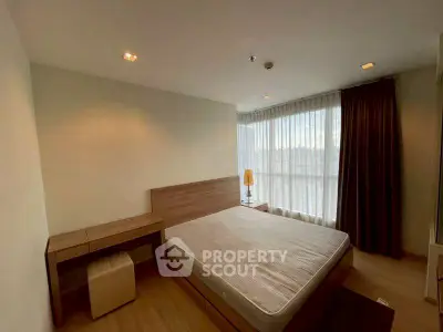 Cozy bedroom with large window and modern furnishings in a stylish apartment.