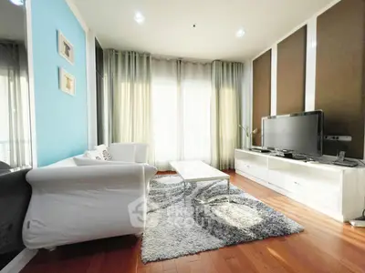 Modern living room with stylish decor, hardwood floors, and natural light through large windows.
