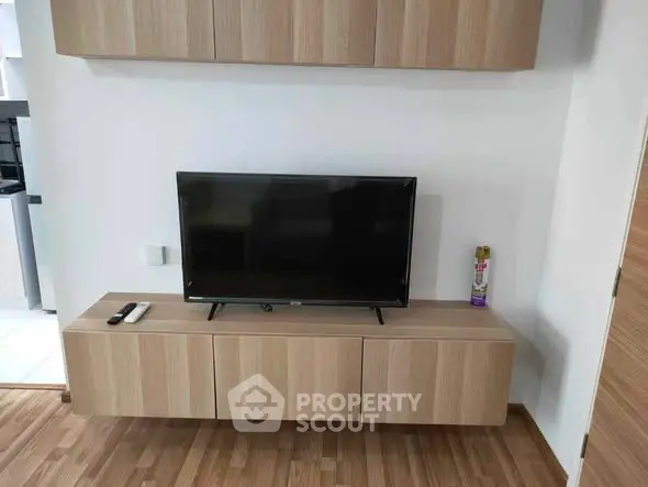Modern living room with sleek wooden TV console and mounted cabinets, showcasing minimalist design.