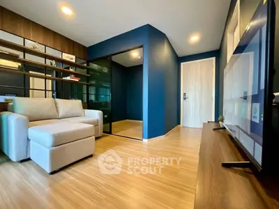 Modern living room with sleek design and wooden flooring, featuring a cozy sofa and large TV.