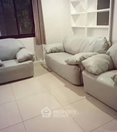 Cozy living room with modern white sofas and tiled flooring.