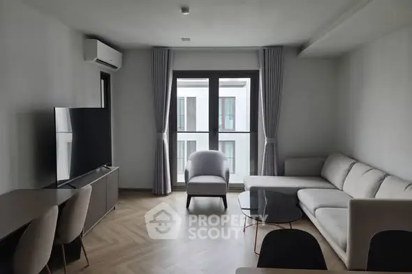 Modern living room with sleek furniture and large window offering natural light.