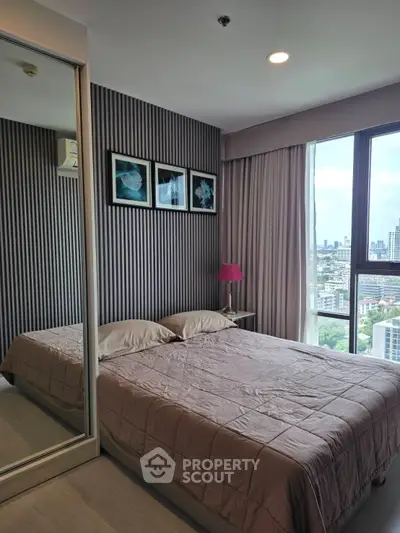 Modern bedroom with city view, featuring stylish decor and large window for natural light.