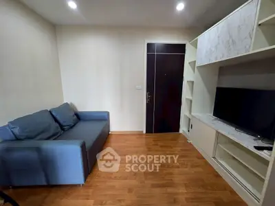 Modern living room with sleek sofa and built-in TV unit, featuring elegant wooden flooring.